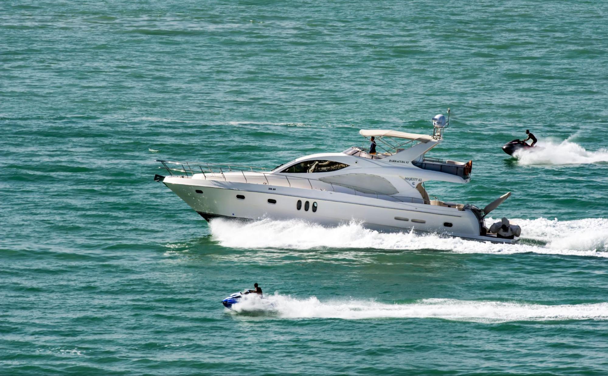 power yacht speeding through Miami water with jet skiers